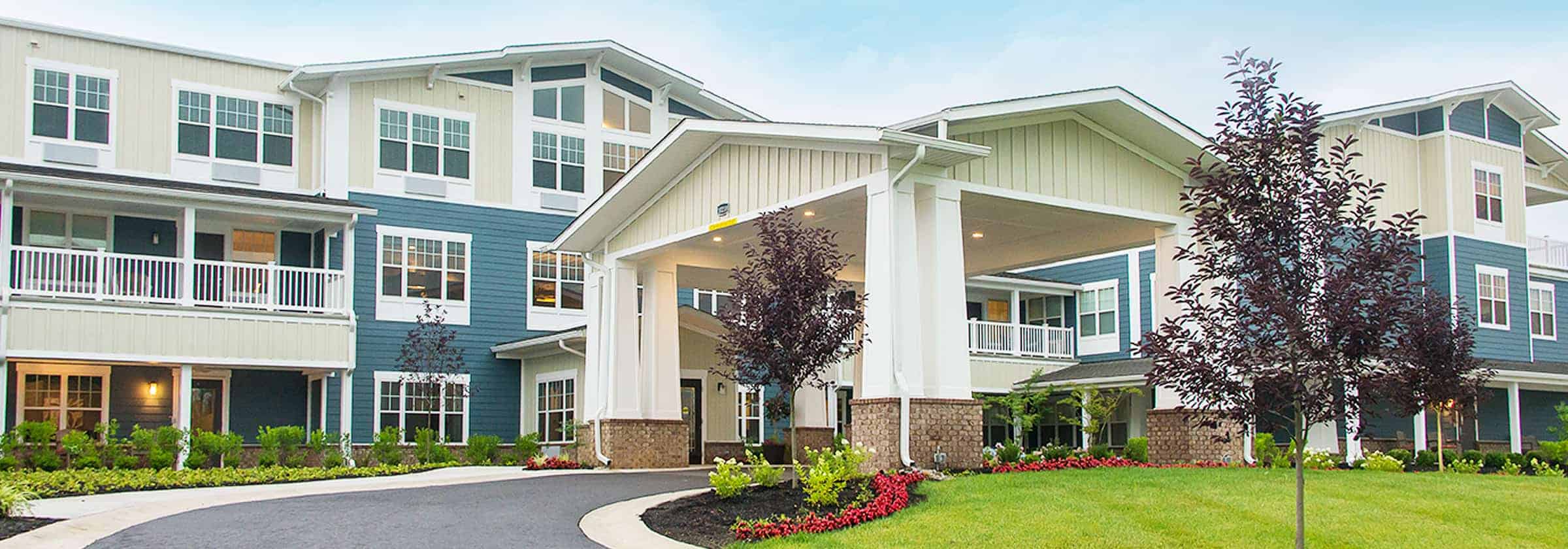 Front view of a blue and white Traditions Management senior living building