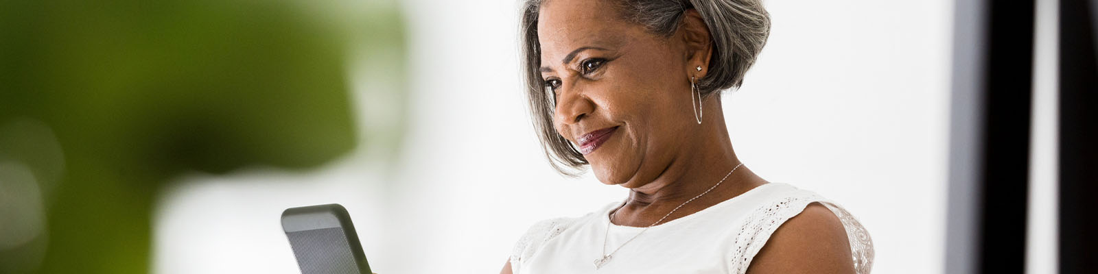 A senior woman sitting down looking at her smartphone
