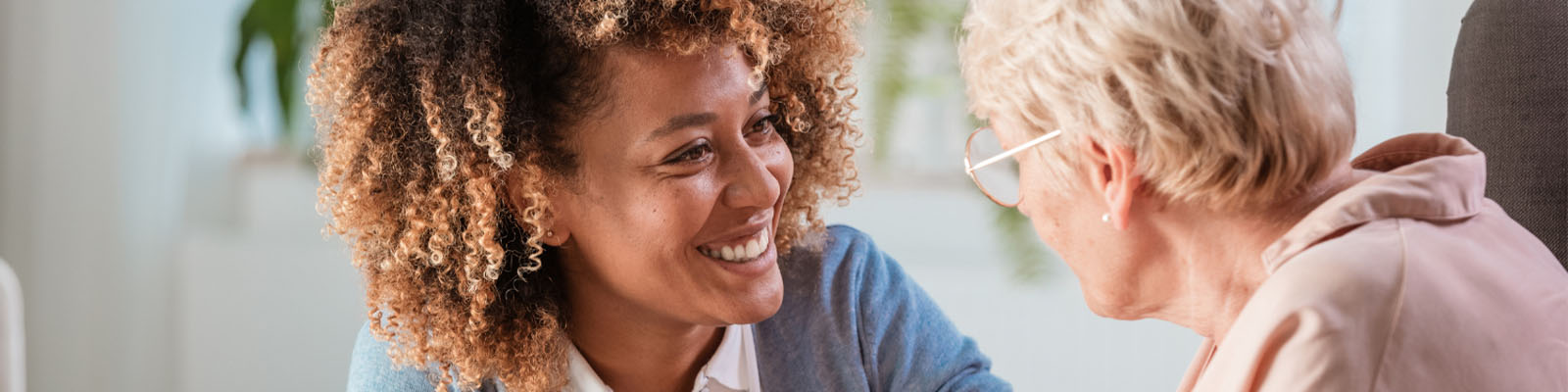 A senior woman and her female nursing assistant looking at each other