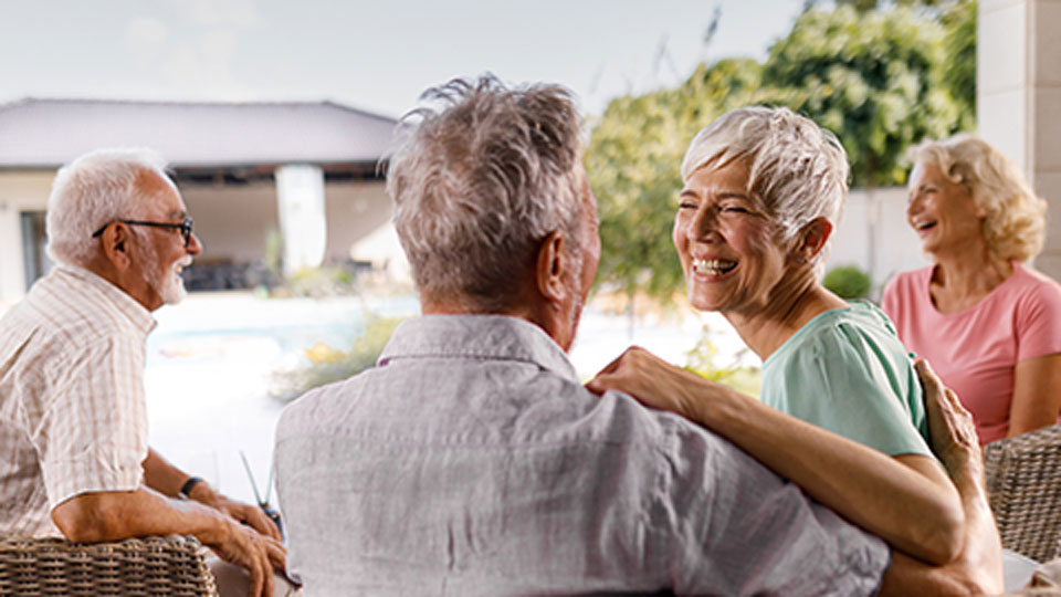 A group of male and female senior living residents sitting on patio furniture outdoors at Traditions of Westfield in Indiana