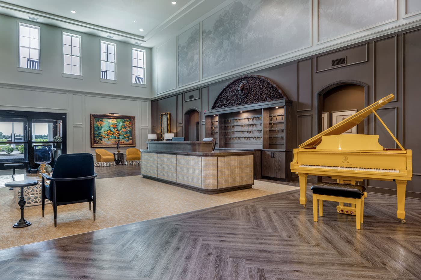 Grand lobby featuring a yellow piano and a front desk with multiple keys hanging at Traditions of Westfield in Westfield, IN.
